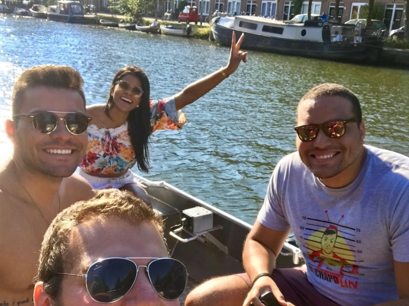 Tre donne e un uomo in abiti bianchi su una barca, dipendente Boats4rent sulla banchina
