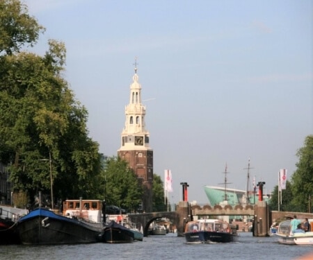 Barca che naviga lungo barche ormeggiate in un vivace canale di Amsterdam.